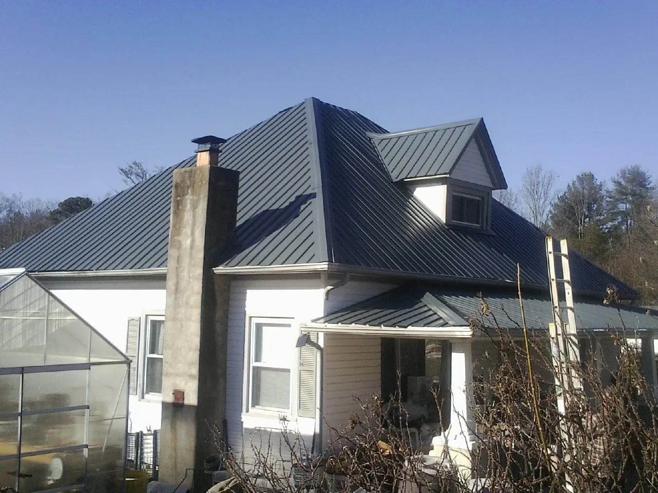 Dark blue standing seam metal roof on a white farmhouse with dormer — Slate & Tile Roof Repair by Roofing Brothers in Grissom Arb