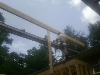 Carpenter setting a ridge beam over a new addition frame — Ice Dam Removal by Roofing Brothers in Grissom Arb