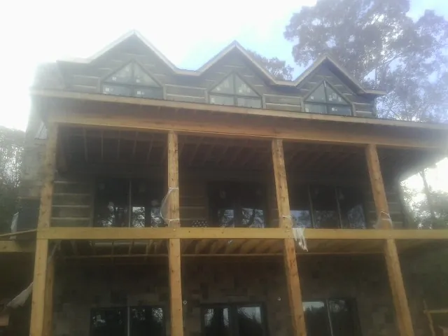Dormers and porch framing on a large log home under construction — Roof Coating work by our crew in Grissom Arb