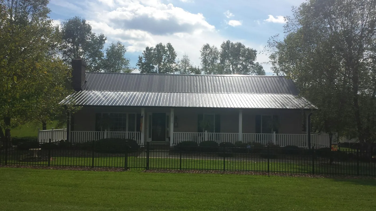 Gray metal roof on a brick ranch with a full width front porch — Gutter Guard Installation work by our crew in Grissom Arb