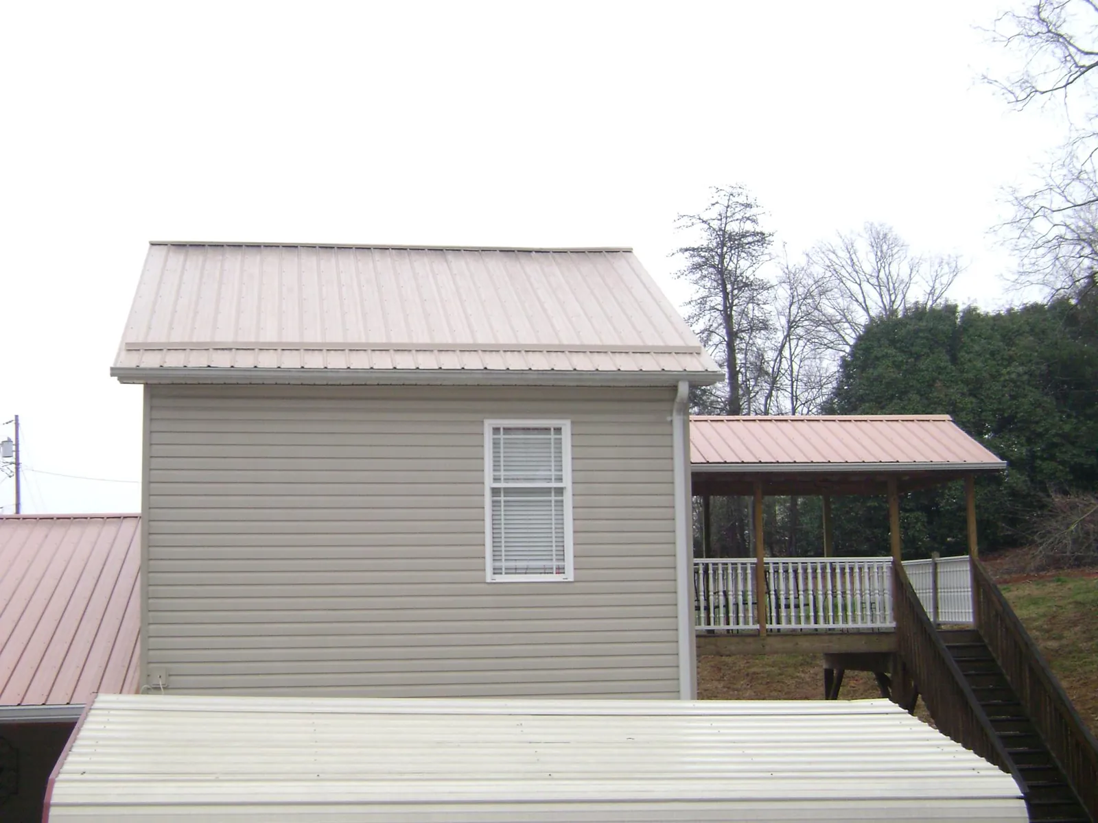 Tan metal roofs on a two story addition and attached porch, from a Roof Replacement job in Grissom Arb
