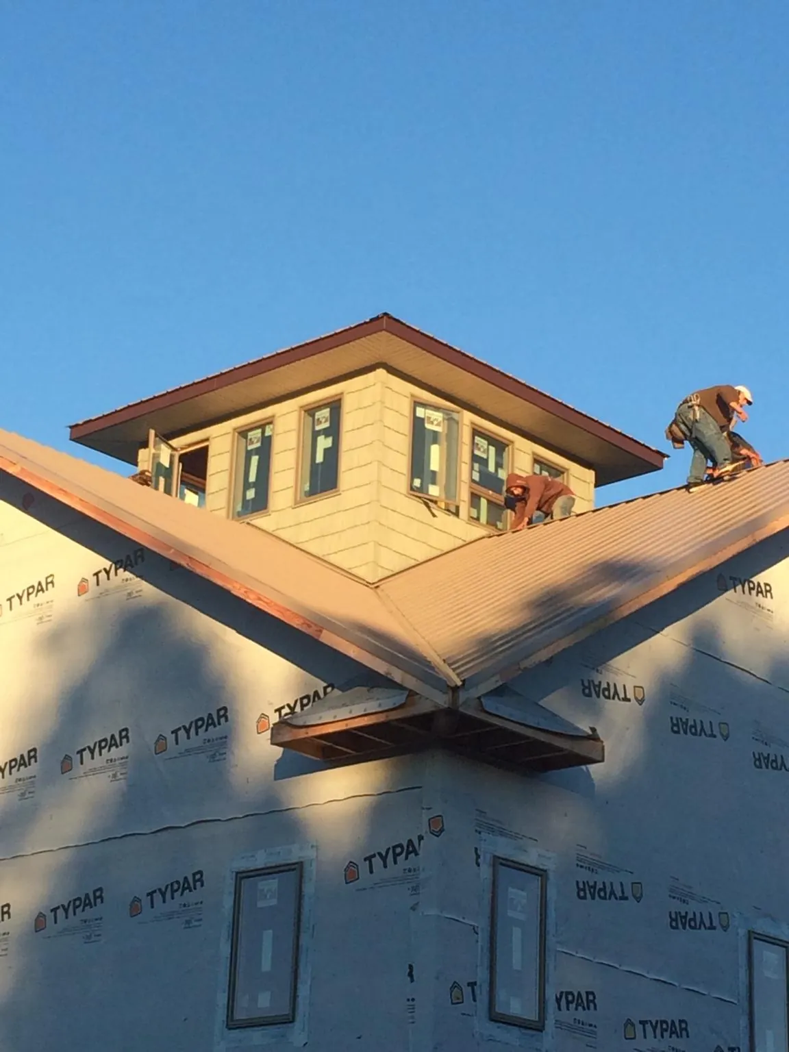 Roofers working around a rooftop cupola on a new metal roof at sunset — Roof Waterproofing in Grissom Arb by Roofing Brothers
